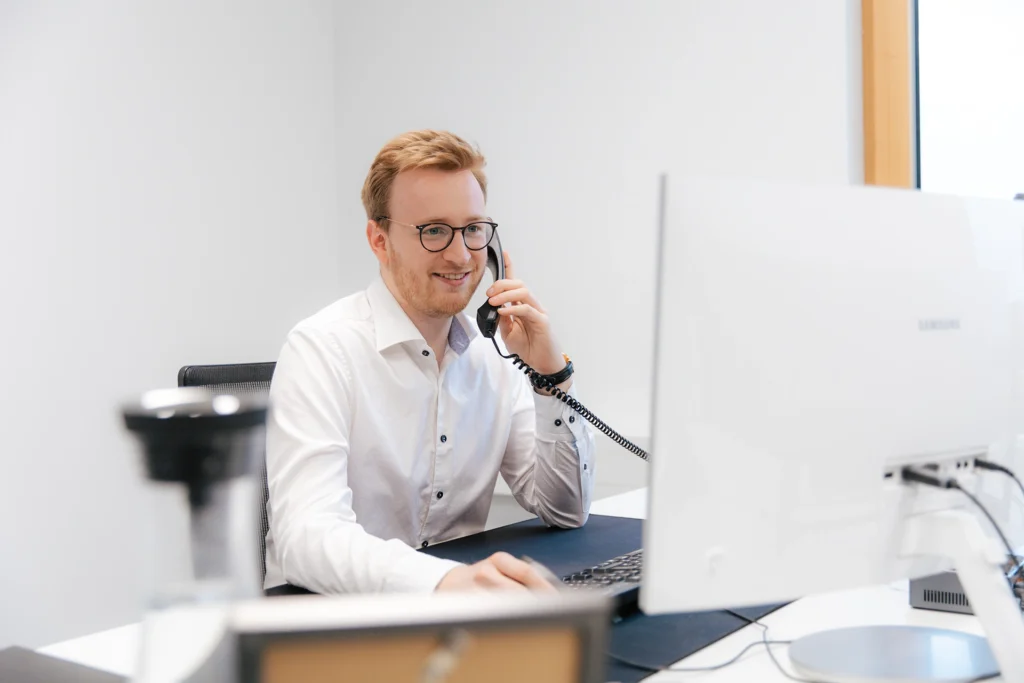 Person sitzt am Schreibtisch und führt ein Telefonat
