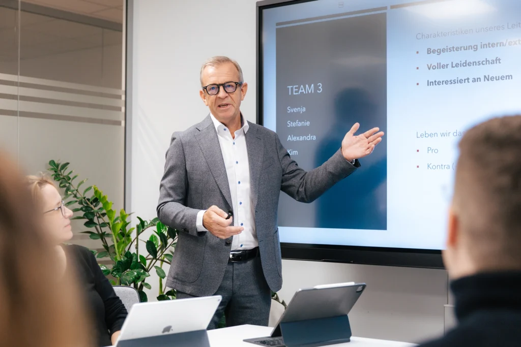 Eine Person steht vor einem digitalen Whiteboard und hält eine Präsentation