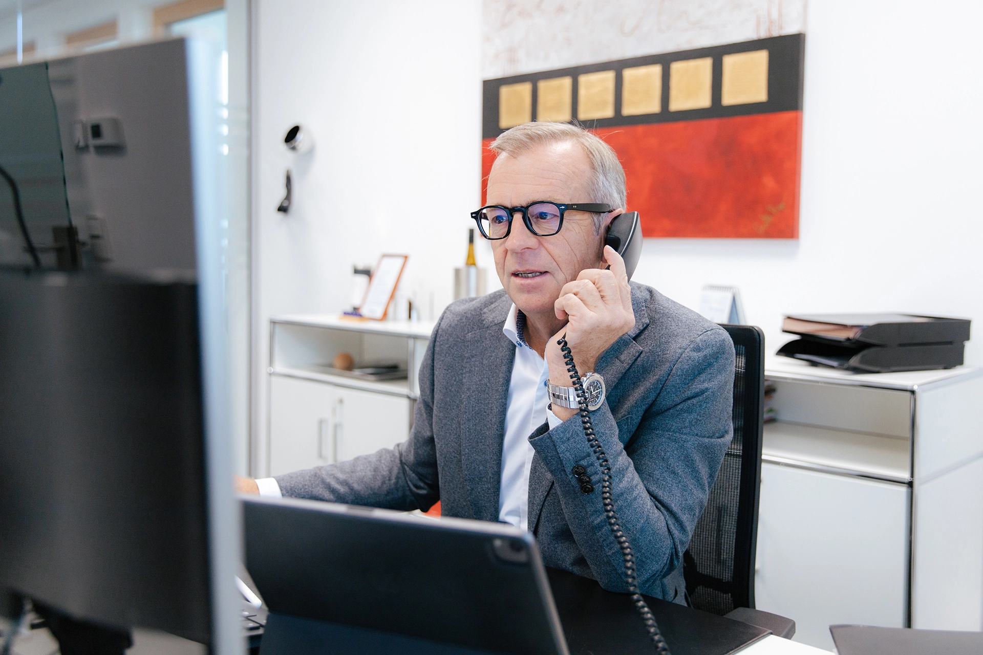 Eine Person sitzt am Schreibtisch und telefoniert