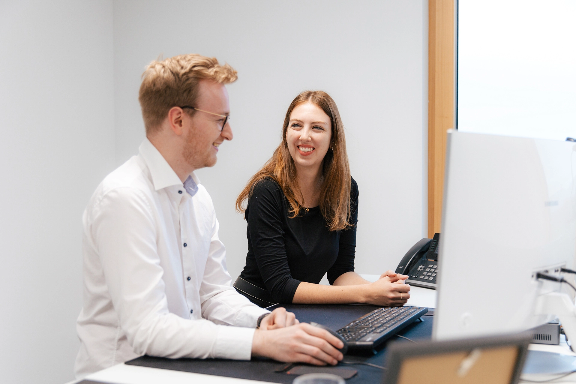 Zwei Personen sitzen am PC und arbeiten gemeinsam